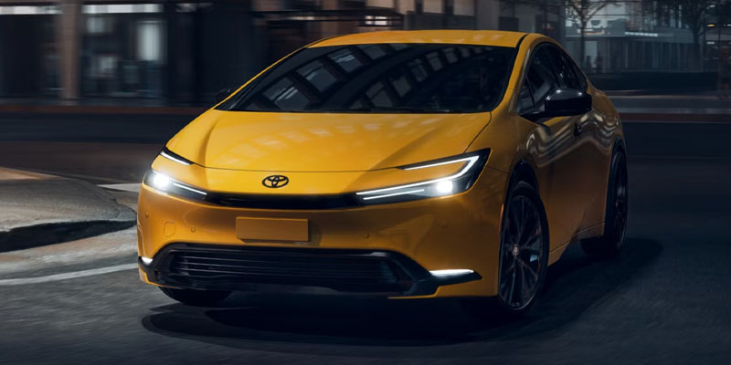 Alt text: A yellow 2026 Toyota Prius driving at night, showcasing its sleek design and modern headlights.