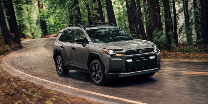 Gray Toyota SUV driving on a winding road through a forest.
