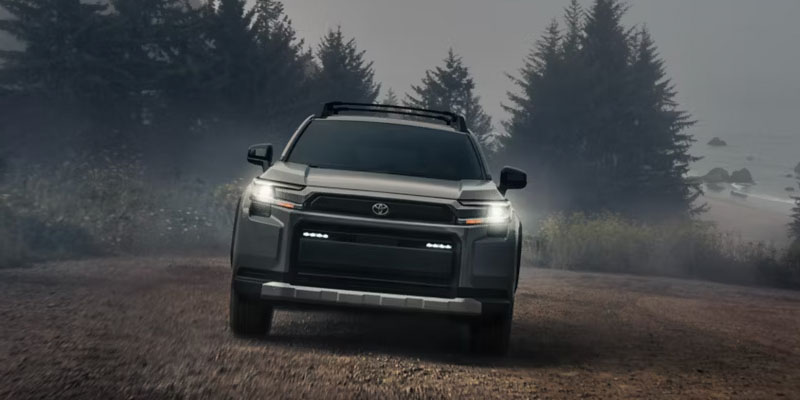 Gray Toyota SUV driving on a dirt road in a foggy pine forest.