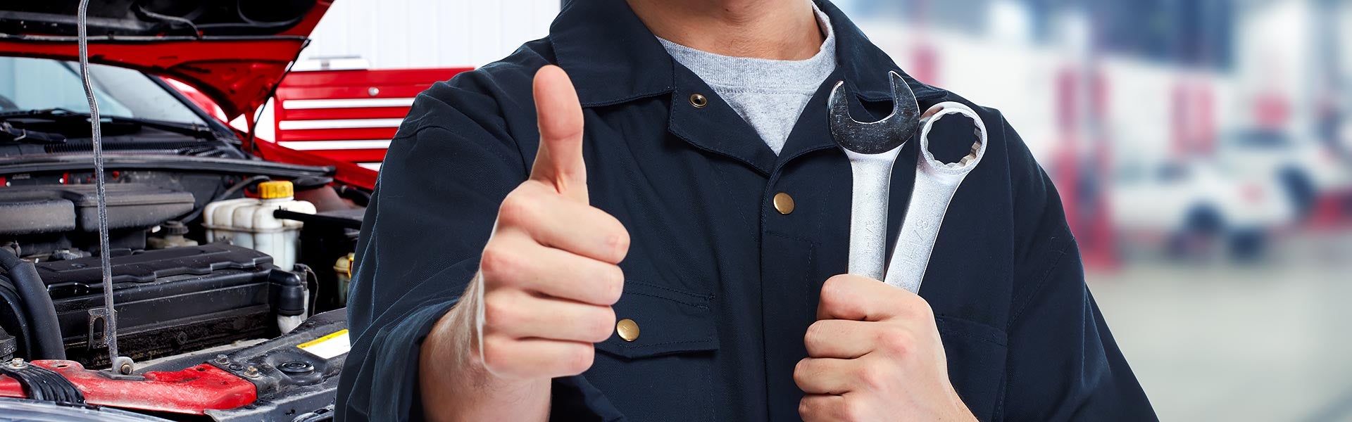 Mechanic holding wrenches and giving a thumbs-up